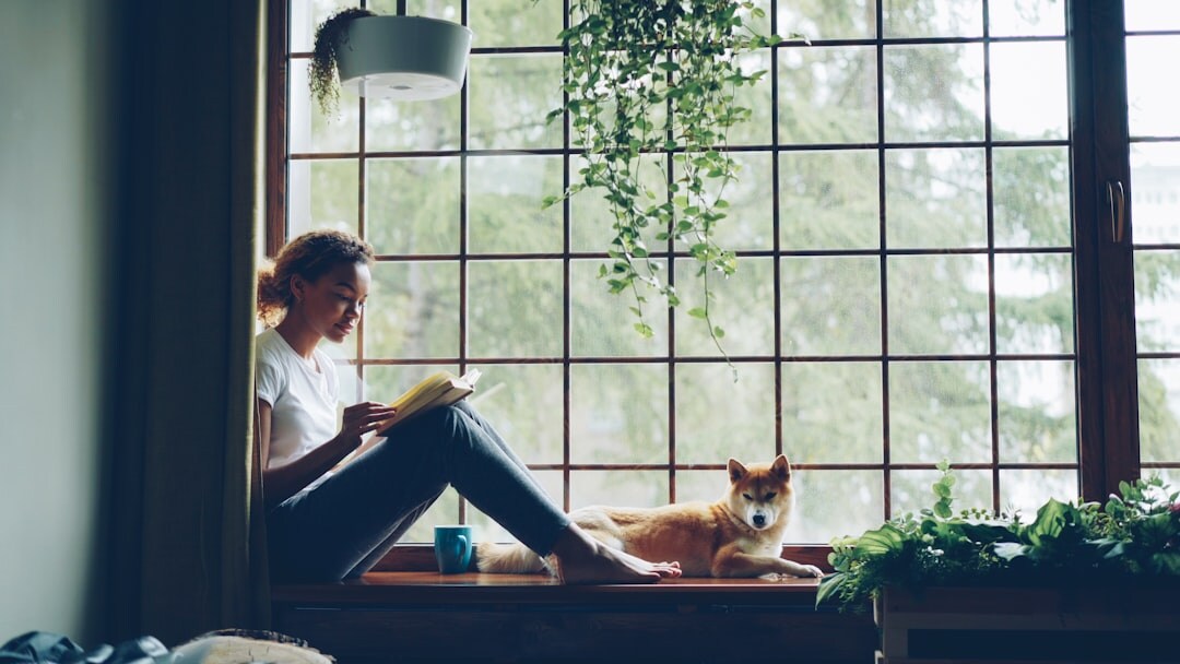 woman reading book by window